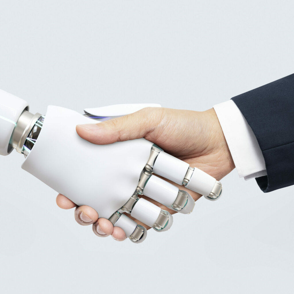 Weiße Roboter Hand gibt Menschenhand mit Anzug einen Handschlag und symbolisiert somit die Digitalisierung der internen Kommunikation